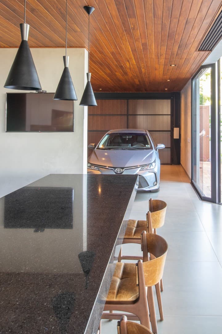 Casa CaCle – garagem com carro, piso em granito polido e integração com o interior