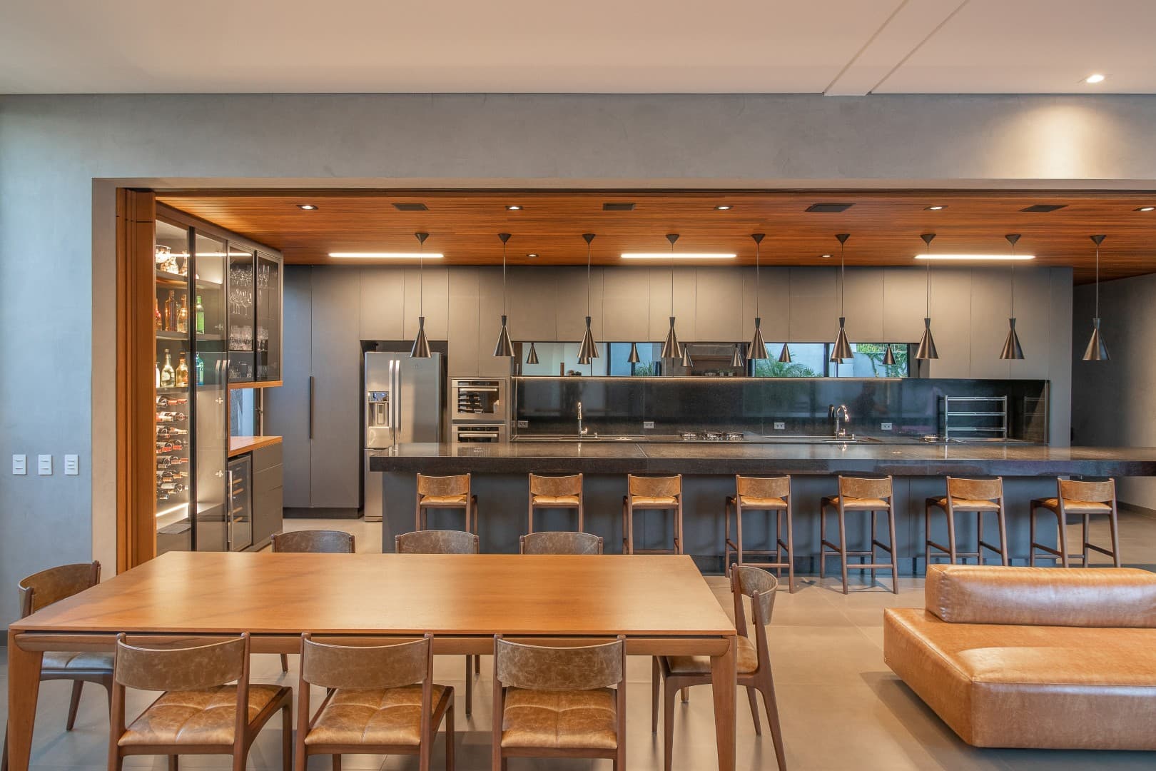Casa CaCle – cozinha gourmet com bancada em granito escuro, pendentes e banquetas